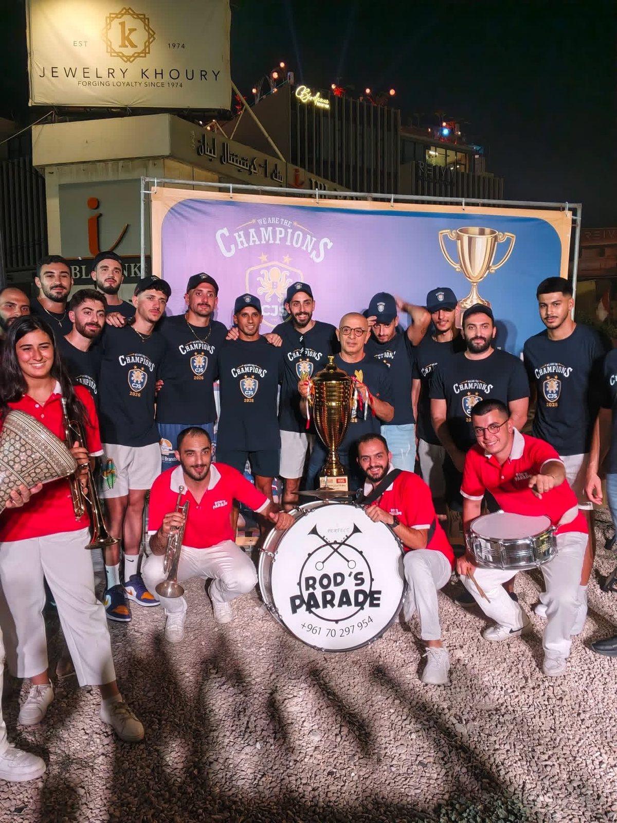 CJS Batroun players celebrating the 2026 title with the trophy and a marching band